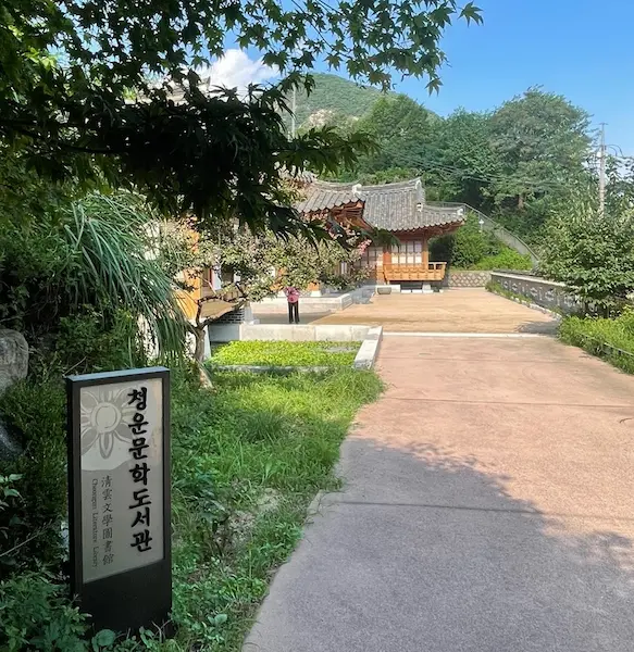 Entrance sign and hanok building of Cheongun Literature Library surrounded by trees and mountains in Seoul