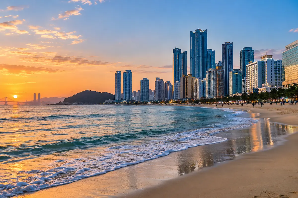 Busan coastline with beach, city skyline and Gwangan Bridge at sunset